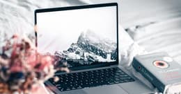 MacBook M1 na posteli vedľa knihy